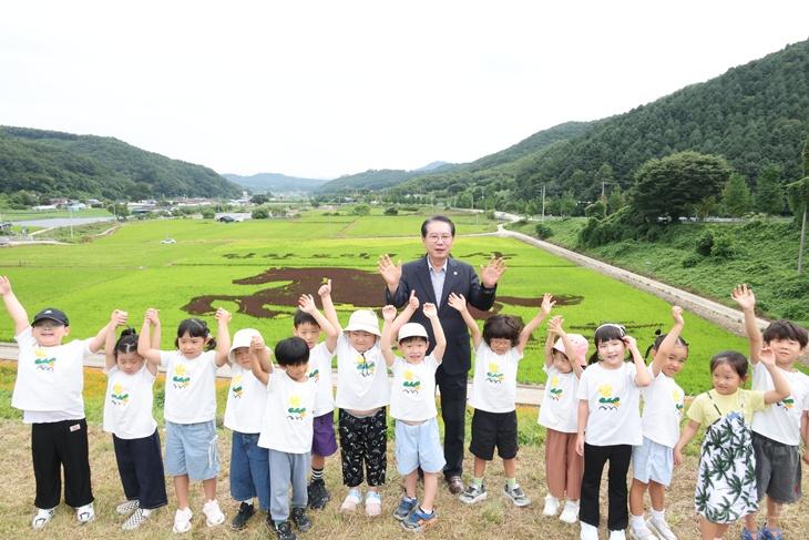 14일 충북 괴산군 문광면 문광저수지 인근 유색벼 논그림 현장에서 어린이집 원생들이 송인헌 괴산군수와 함께 올해의 주제인 `붉은 말`을 바라보며 기념사진을 찍고 있다.jpg