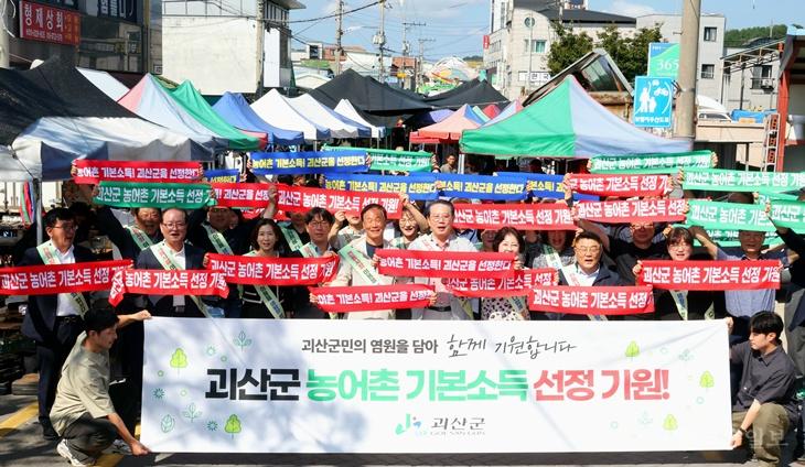 23일 괴산전통시장에서 열린 장보기행사에 송인헌군수, 이한배 기업경영인협의회장, 이정우 상인회장 등 관계자 50여명이 농어촌 기본소득 선정을 기원하는 결의대회를 펼치고 있다.jpg